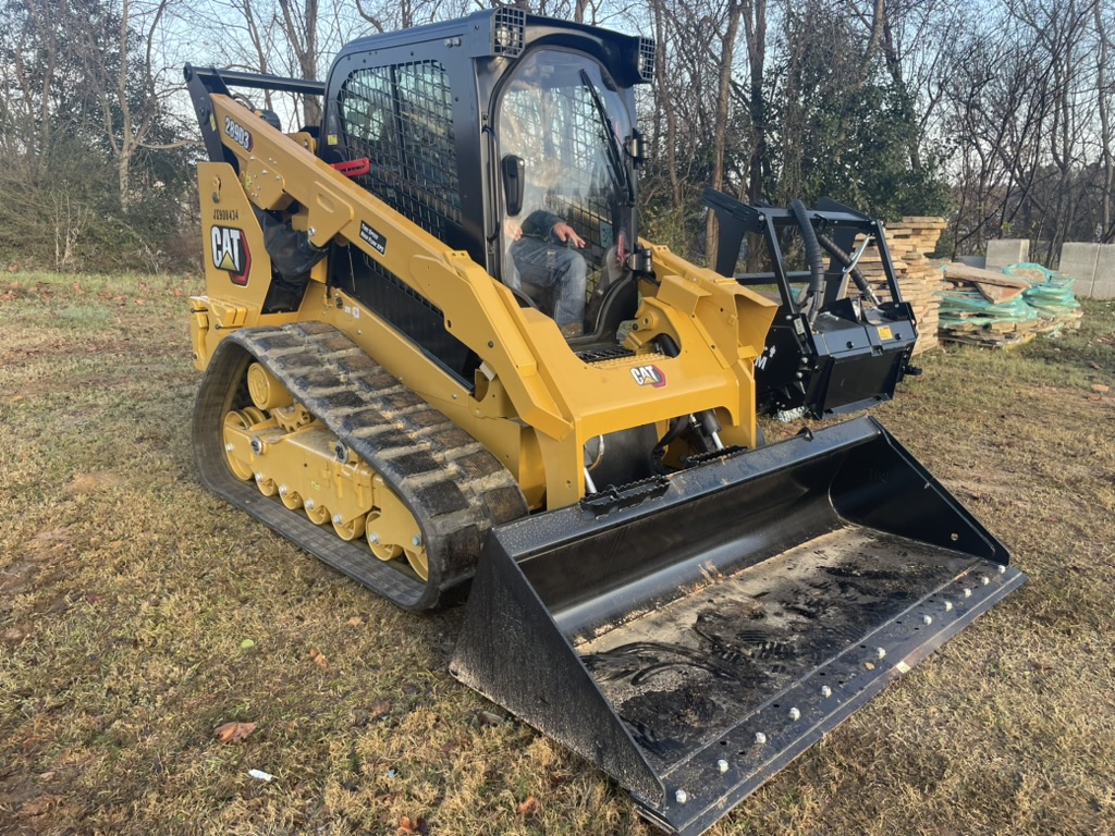 CAT track loader with grading bucket, operator in cab
